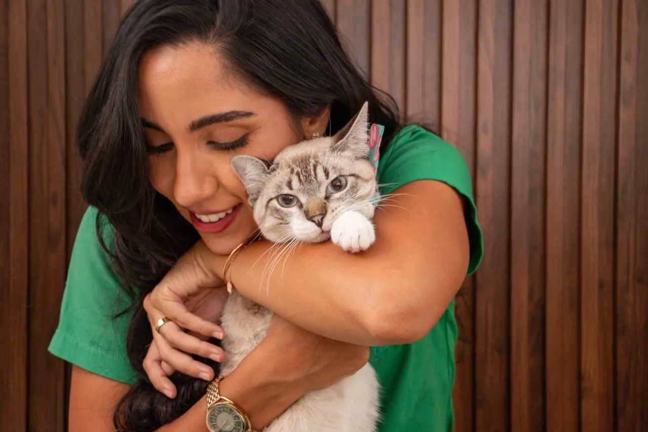 Dra. Natália abraçando com carinho um gato de olhos azuis