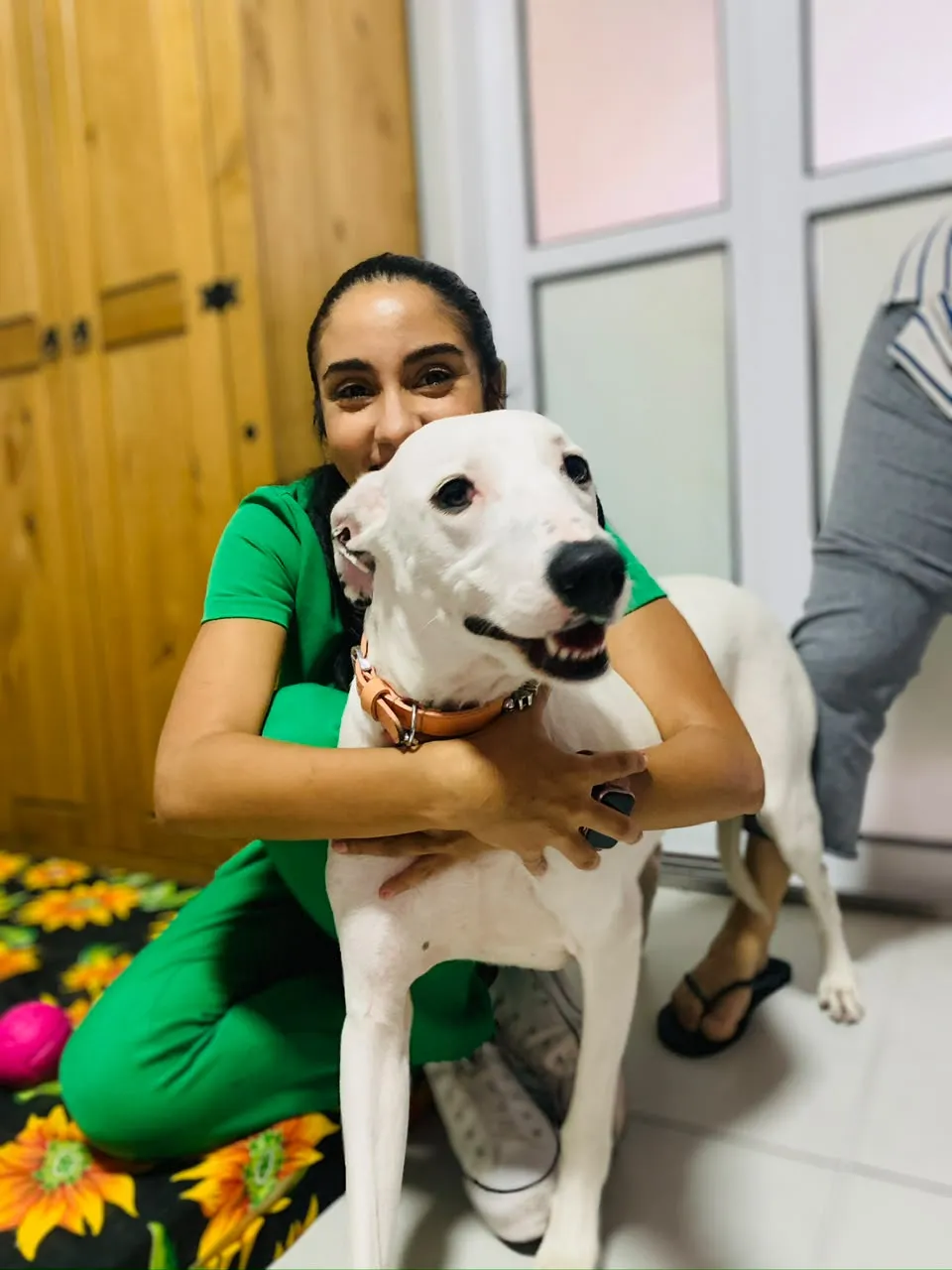 Dra. Natália abraçando um cachorro branco após a consulta